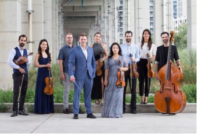 Photograph of the Stratton Soloists holding musical instruments standing outdoors.